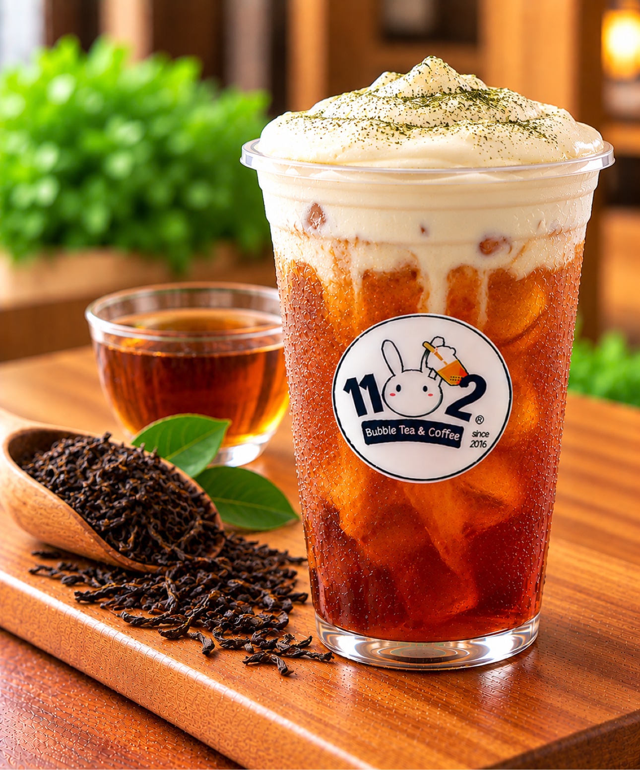 Macchiato black tea with cream in a cup with the 1102 shop logo sticker